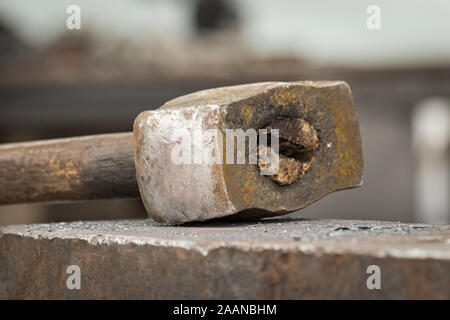 Old rusty hammer lies on the anvil. Blacksmith, metalsmith, farrier tools. Close view. Stock Photo