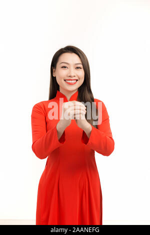 Young Asian girl in traditional ao dai dress smiling and greeting, celebrating Lunar New Year or spring festival Stock Photo