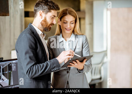 Two strictly dressed office employees working with digital tablet in the office Stock Photo