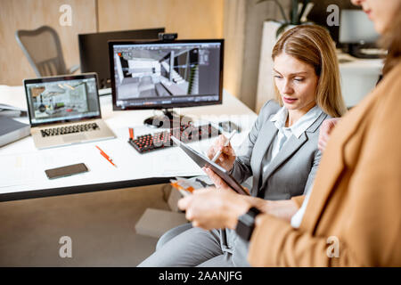 Strictly dressed office employees working with digital tablet and computers at the architectural bureau. Concept of an architectural business and digital designing Stock Photo