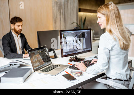 Creative office employees making interior design on the computers, sitting at the modern office of architectural firm. Concept of 3d modeling and digital Interior designing Stock Photo