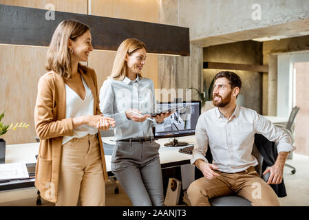 Creative office employees working on some architectural project, talking at the working place of the modern office studio. Concept of an architectural business and creative work Stock Photo