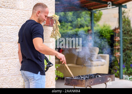 Barbecue Grill. Young Happy Man Preparing BBQ In The Back Yard. Bearded Handsome Athlete Man Grilling On the Garden. Stock Photo