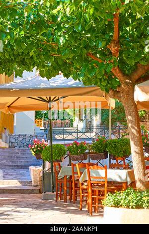 Street cafe with tables in a shade of trees in Plaka district in Athens, Greece Stock Photo