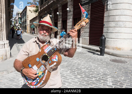 A Cuban street musician playing his guitar to tourists in Plaza San Francisco  in the old town of Havana in Cuba. Stock Photo