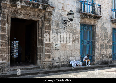 A street artist displaying his artwork for sale to tourists outside the Museo  de Arte Colonial in Plaza de la Catedral in the old town of Havana, (Haba Stock Photo