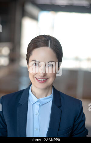 Beautiful business lady wearing dark jacket smiling while feeling motivated Stock Photo
