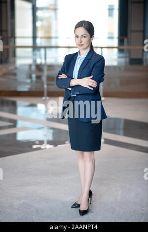 Business lady wearing skirt and jacket standing in spacious light business center Stock Photo