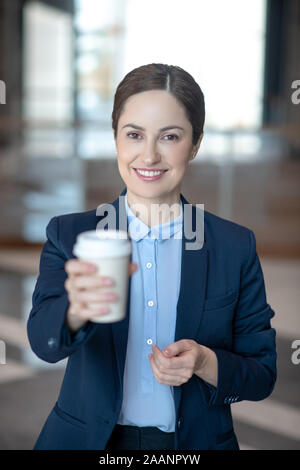 Cheerful business lady holding her takeaway coffee in the morning Stock Photo