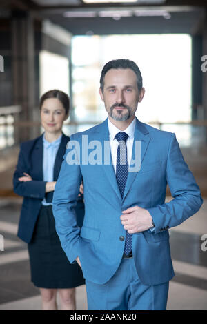 Serious bearded businessman wearing elegant suit standing in the office Stock Photo