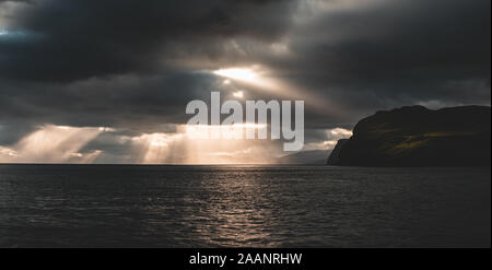 Beautiful rays of sun breaking through the clouds in Sandoy and Hestur ferry travel, faroe islands Stock Photo