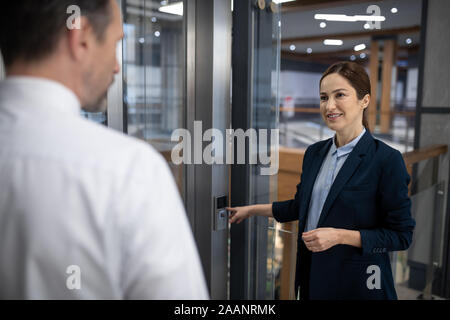 Dark-haired businesswoman pressing the button while waiting for elevator Stock Photo