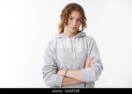 Serious-looking attractive young teenage sportswoman with ginger hair freckles wearing hoodie cross arms self-assured strong pose dressed-up morning Stock Photo