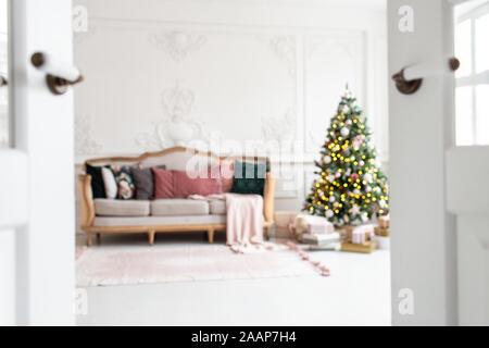 Blurred photo of white sofa standing next to christmas tree surrounded by gift boxes. Stock Photo