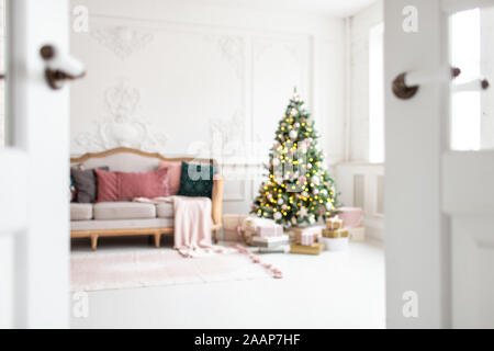 Blurred photo of white sofa standing next to christmas tree surrounded by gift boxes. Stock Photo