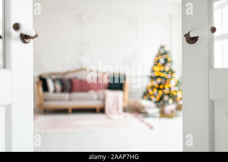Blurred photo of white sofa standing next to christmas tree surrounded by gift boxes. Stock Photo