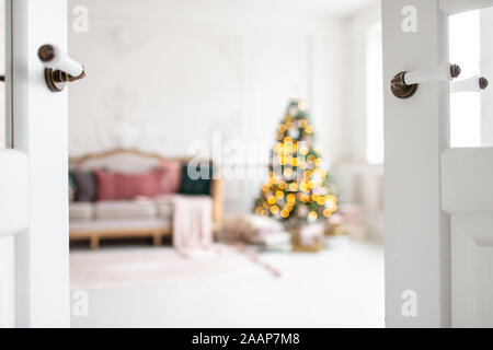 White sofa standing next to christmas tree surrounded by gift boxes. Selective focus. Stock Photo