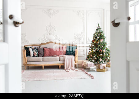 White sofa standing next to christmas tree surrounded by gift boxes. Selective focus. Stock Photo