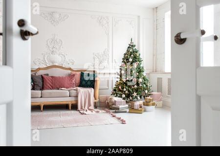 White sofa standing next to christmas tree surrounded by gift boxes. Selective focus. Stock Photo