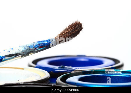 Tins of model paint and a fine paint brush isolated on a white background Stock Photo