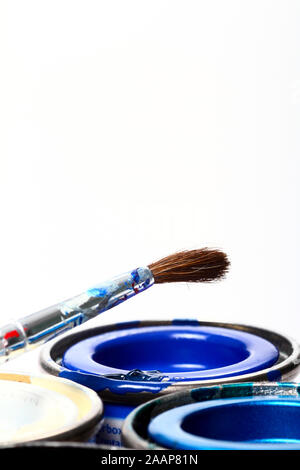 Tins of model paint and a fine paint brush isolated on a white background Stock Photo