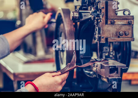 Female shoemaker hands stitching a part of the shoe in the handmade footwear industry. Selective focus. Stock Photo