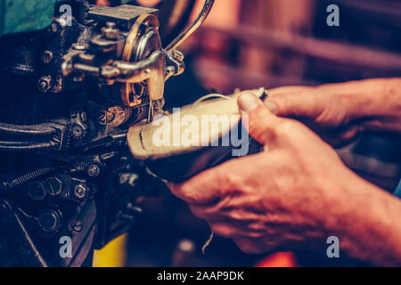 Hands of an experienced shoemaker stitching a part of the shoe in a shoe factory. Selective focus. Stock Photo