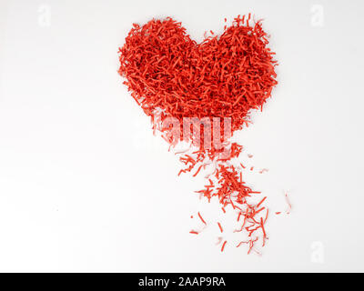 Red shredded paper in shape of heart on blue background. Heart made of shredded paper. Recycling concept. decaying heart Stock Photo