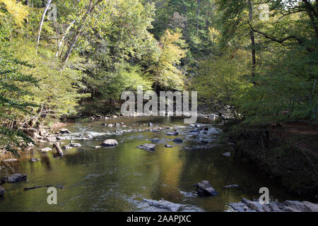 The Eno River flowing over rocks and boulders through a forest in Eno River State Park, North Carolina, USA, on a sunny day Stock Photo