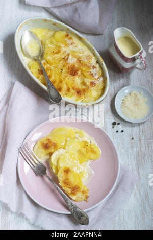 French dish Gratin Dauphinois in ceramic form on a light background. Rustic style. Stock Photo