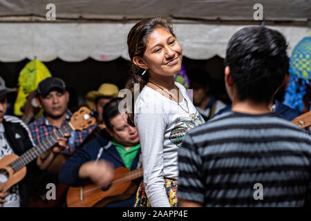 Zapateado dancers perform a traditional folk dance during a neighborhood Huapango in Santiago Tuxtla, Veracruz, Mexico. The dance involves dancers striking their shoes on a wooden platform while a large group of musicians play string instruments. The gatherings take part in the Los Tuxtlas mountain villages for single people to meet. Stock Photo