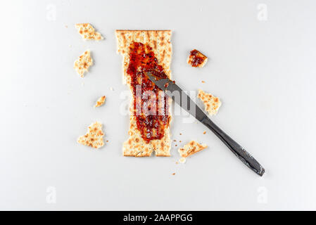 Pesach celebration concept. Matzah, an leaven bread served at the Jewish Passover in overhead view with strawberry preserves. Stock Photo