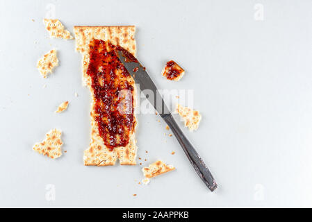 Pesach celebration concept. Matzah, an leaven bread served at the Jewish Passover in overhead view with strawberry preserves. Stock Photo