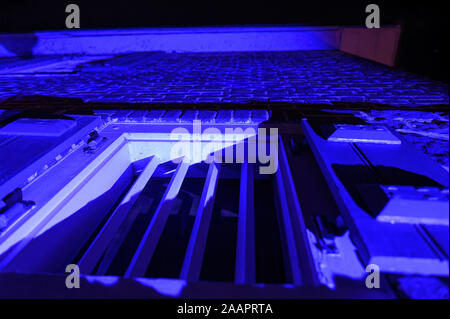 Old-fashioned window with strong metal bars at night, illuminated in blue Stock Photo