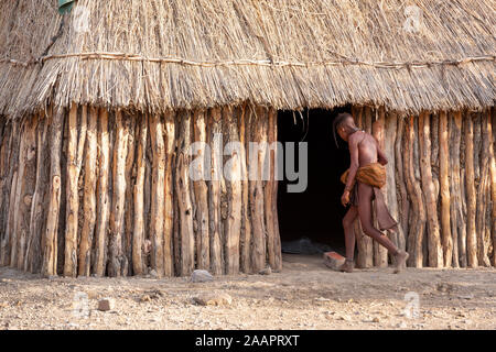 A kid walks into a hut in a Himba tribal village in Namibia, Africa Stock Photo