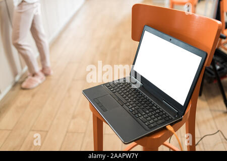 Notebook with clipped display placed on a orange chair, workplace with hardware equipment Stock Photo