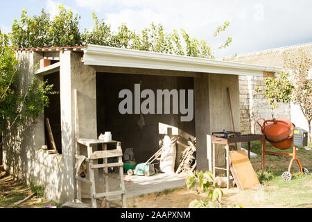 Unfinished concrete building in the garden with fruit falling trees Stock Photo