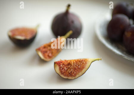 Fig slices and whole figs lie on a white table. Stock Photo