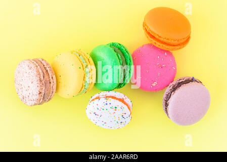 Sweet colorful French macaroon biscuits on pastel yellow background, top view Stock Photo