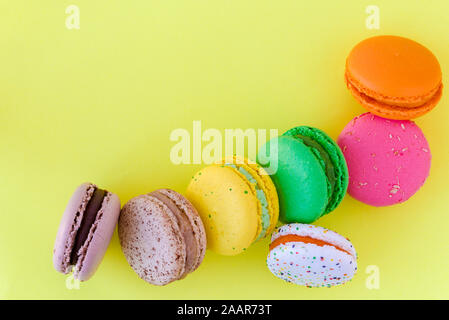 Sweet colorful French macaroon biscuits on pastel yellow background, top view Stock Photo