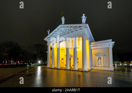 Figures of two young people at the Cathedral Basilica of Stanislaus and Ladislaus of Vilnius on a dark December evening in Square, Lithuania Stock Photo