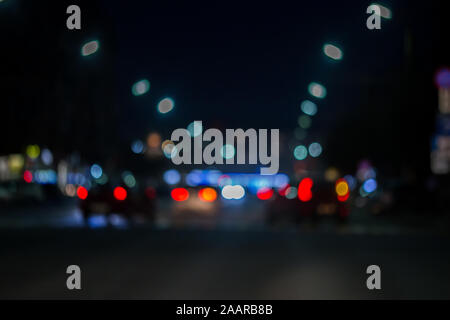 defocused view from the car window with blurry lighting of city traffic on the city streets at night, blurred background. Stock Photo