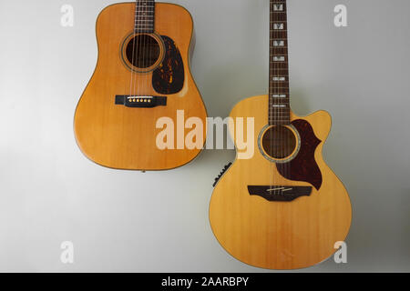 Two acoustic guitars hanging on a grey wall Stock Photo