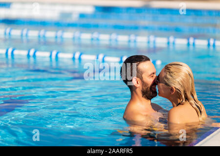 Young Couple is swimming in the pool and laughing. Summer vacation Stock Photo