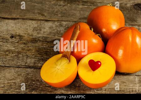Ripe orange persimmon fruit.Kaki fruit on wooden table.Slices of persimmon.Set of kakis. Fruits of Kaki Persimmon (Diospyros kaki) in japanese autumn Stock Photo