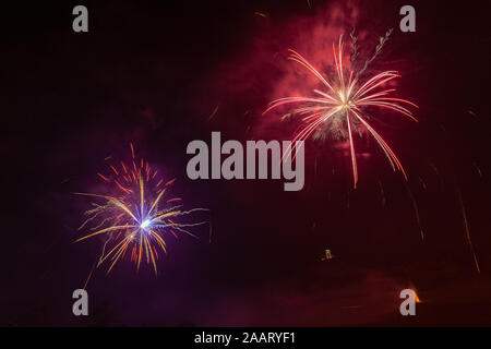 Beautiful couple of red and orange fireworks over trees silhouette Stock Photo
