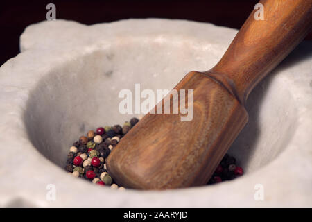 Mixed multi colored peppercorns in mortar and pestle. Close-up of Organic spices: black peppercorns, green peppercorns, white pepper, pink peppercorns Stock Photo