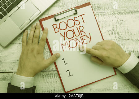 Text sign showing Boost Your Money. Business photo text increase your bank saving using effective methods Hand hold writing equipment tool near modern Stock Photo