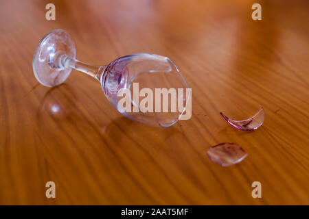 Broken and dirty wine glass on a wooden table Stock Photo