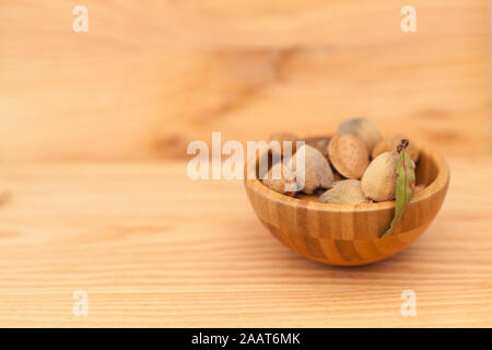Shell almonds in wooden bowl on wooden table. Almond concept with copyspace. Stock Photo